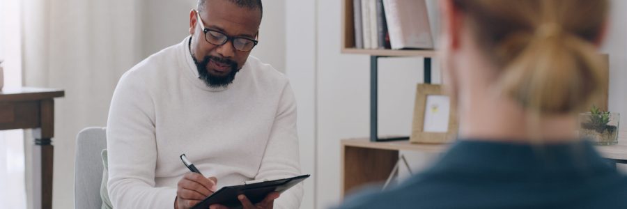 Black man, psychology and writing note with woman patient in counseling appointment for help, support and consulting. Psychologist listening, advice and helping client with mental health or anxiety